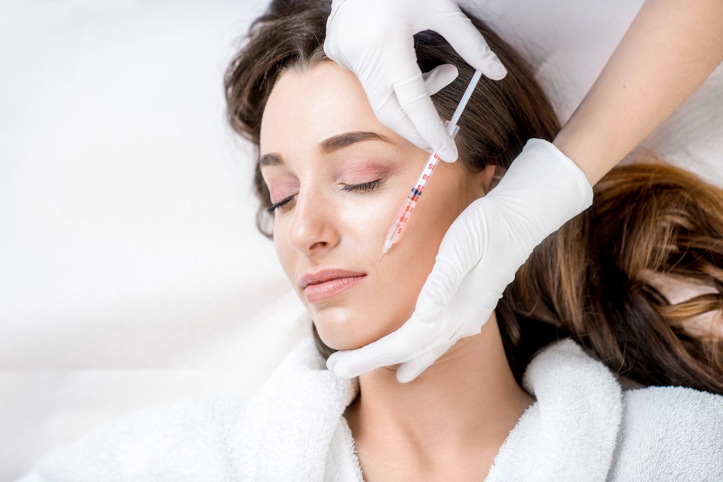 Woman getting anti wrinkle injection, to cheek