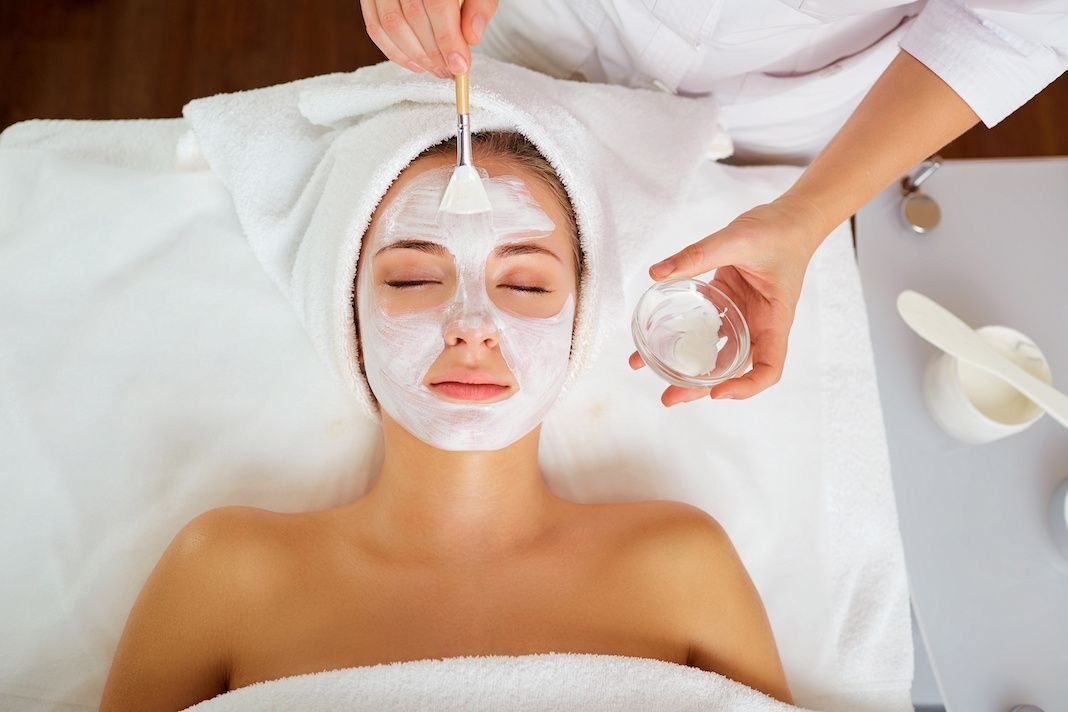 Woman getting chemical peel treatment, brush applying gel/cream, top angle