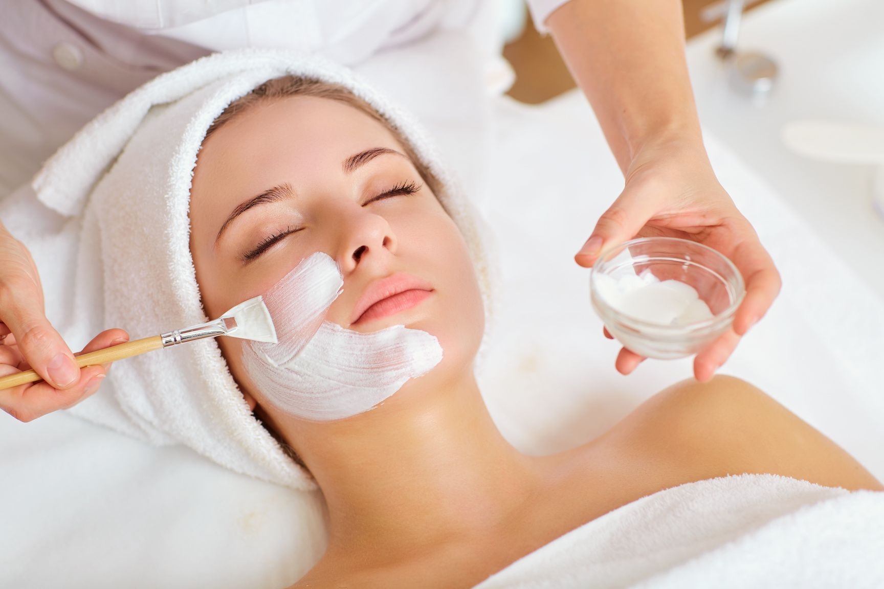 Woman getting chemical peel treatment, brush applying gel/cream