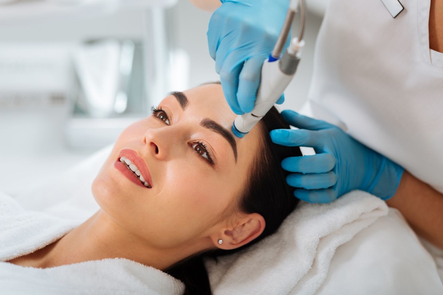 Woman happy getting hydrafacial treatment