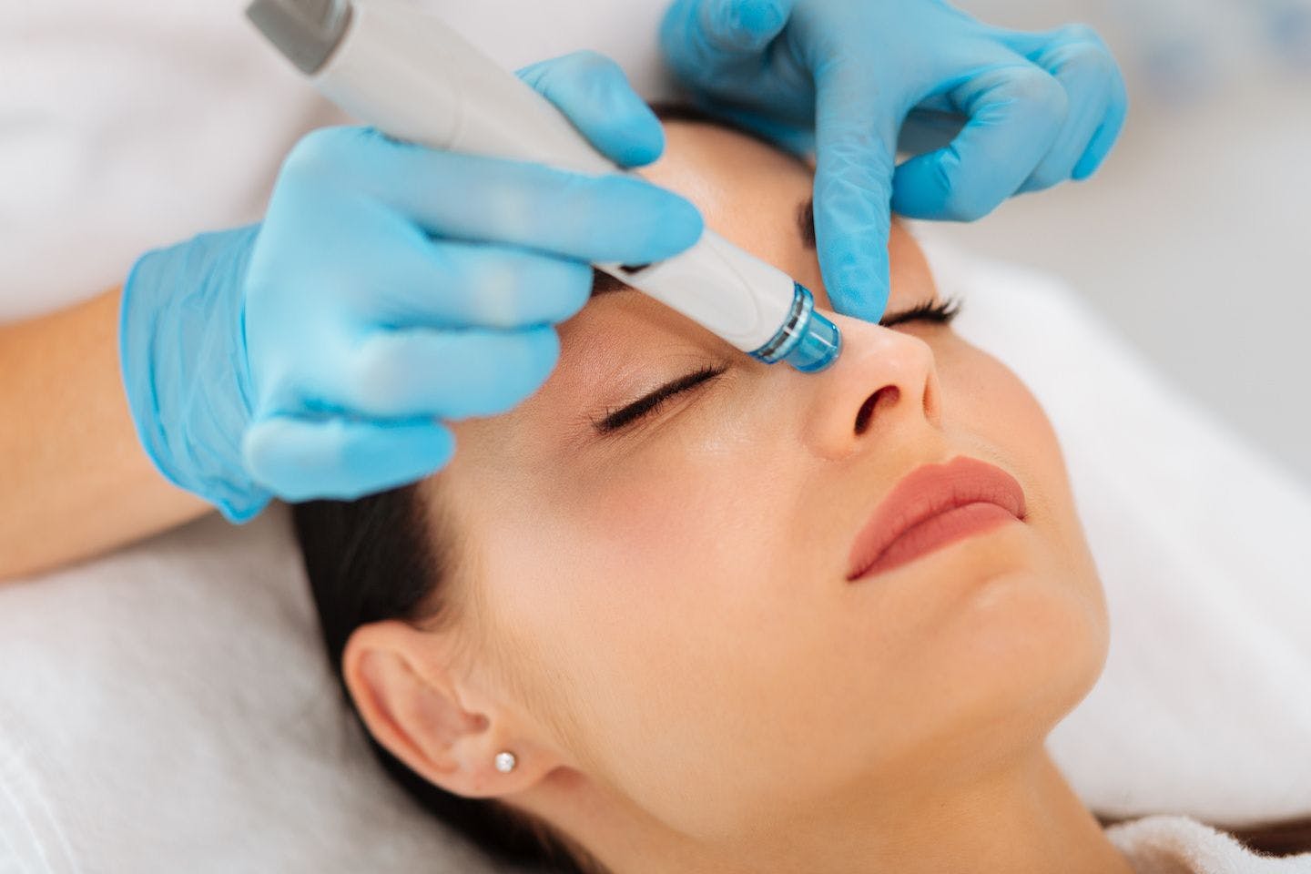 Woman happy getting hydrafacial treatment on her nose