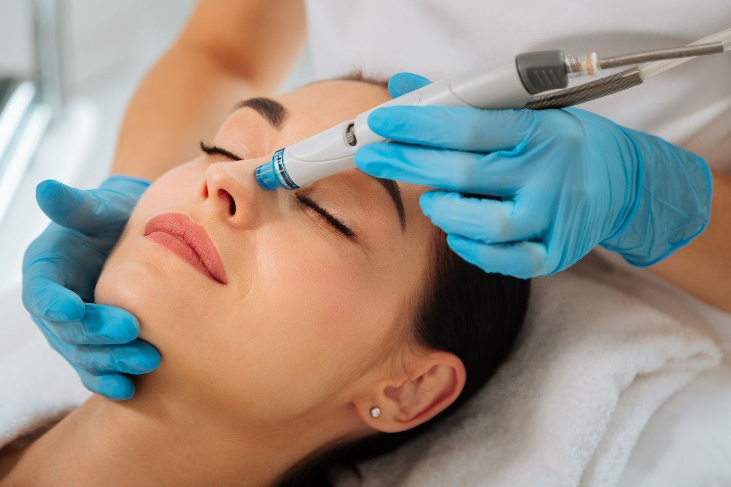 Woman happy getting hydrafacial treatment on her nose