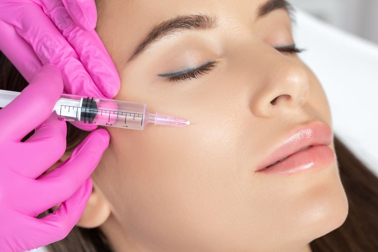 Woman getting platelet rich plasma facial, injecting into cheek